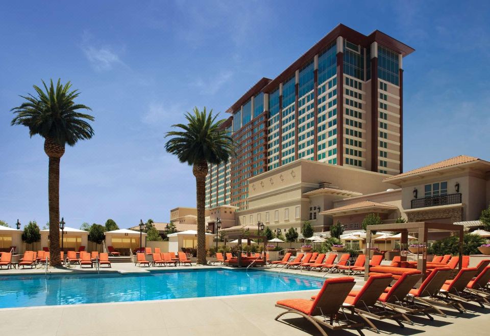 a large hotel with a pool surrounded by lounge chairs and palm trees , creating a relaxing atmosphere at Thunder Valley Casino Resort