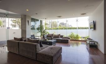 a spacious living room with a large couch , multiple chairs , and a dining table in the background at Long Beach Hotel