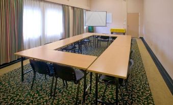 a conference room with a long table and chairs , curtains , and a whiteboard , set up for a meeting at Red Lion Inn and Suites Victoria