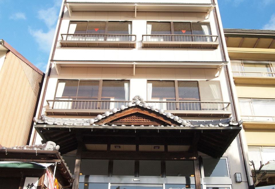 a tall building with multiple balconies and a storefront on the ground floor , surrounded by trees at Sakuraya