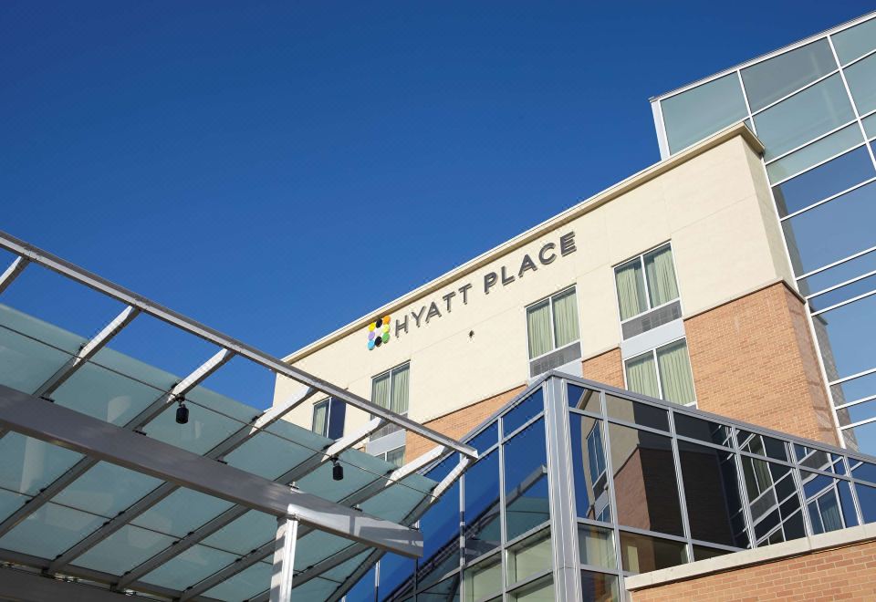 a hyatt place hotel with a large glass entrance and a blue sky in the background at Hyatt Place Saratoga Malta