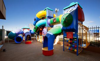a colorful playground with various play structures , such as slides , swings , and climbing structures , for children to enjoy at Wilsonton Hotel