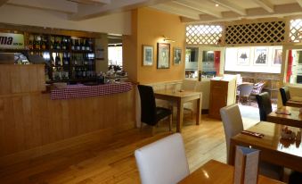 a dining area with a wooden table and chairs , as well as a bar in the background at The Atherstone Red Lion Hotel