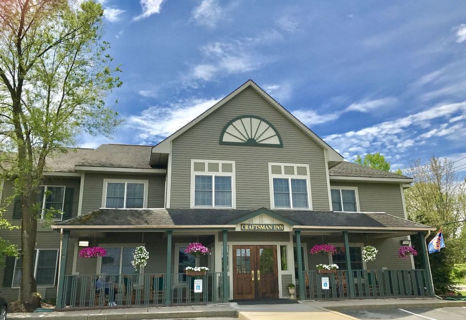 a gray building with a red roof and large windows is surrounded by flower arrangements at The Craftsman Inn & Suites