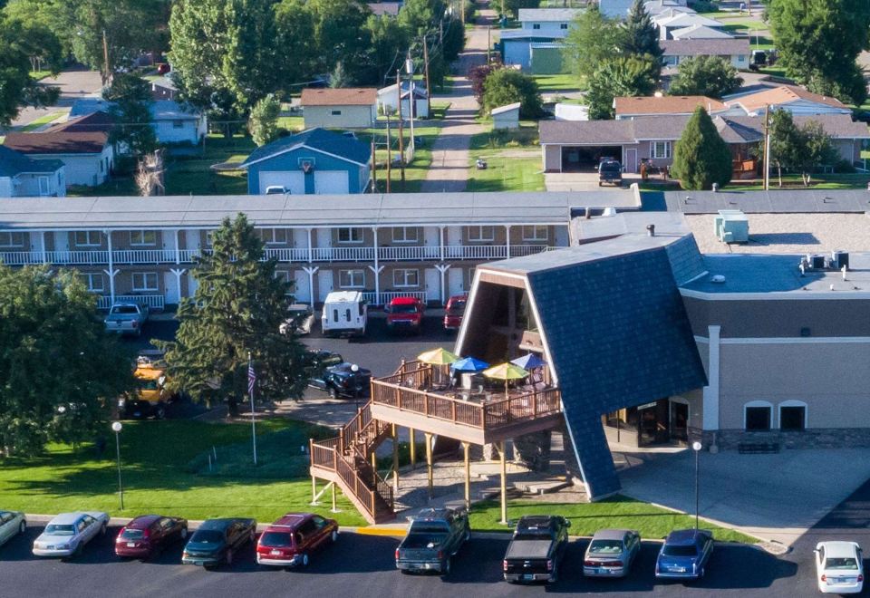 a parking lot with cars and a house with a balcony in the center of the scene at Wrangler Inn Mobridge