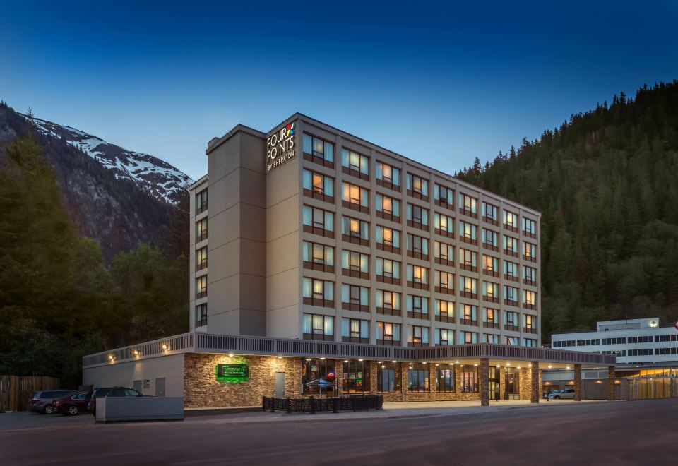 a large hotel with a stone exterior and several windows is lit up at night at Four Points by Sheraton Juneau