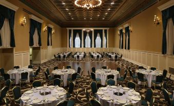 a large banquet hall filled with round tables and chairs , ready for a formal event at Gettysburg Hotel