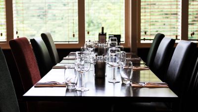 a long dining table set for a meal , with multiple wine glasses and silverware arranged neatly on the table at Village Hotel Liverpool