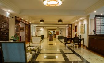 a spacious lobby with high ceilings , marble floors , and multiple chairs arranged around a coffee table at Hotel Home Green Home