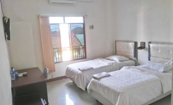 a hotel room with two beds , white bedding , and a view of the balcony through the window at Avicenna Hotel