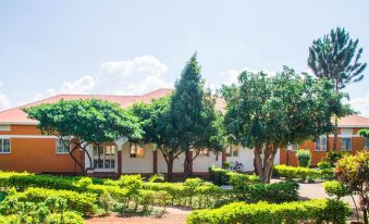 a brick building surrounded by trees and bushes , with a bicycle parked in front of it at Country Inn Masindi