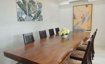 a long wooden table with chairs is set up in a room with a hanging light and a painting on the wall at The Mansion