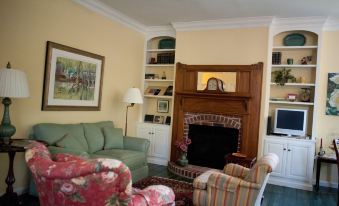 a cozy living room with a green couch , a red armchair , and a fireplace at Green Tree Inn