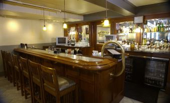 a bar area with wooden furniture , including a counter and chairs , as well as a dining table at Midland Railroad Hotel