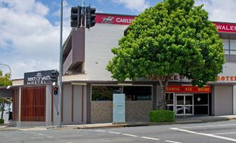 a building with a red sign on the front , located on a busy city street at Prince of Wales Hotel