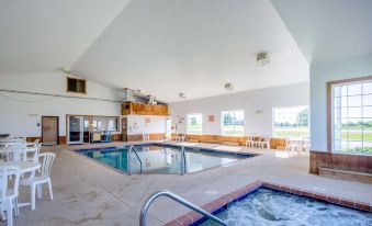 a large indoor pool with a hot tub and lounge chairs is surrounded by windows at Quality Inn