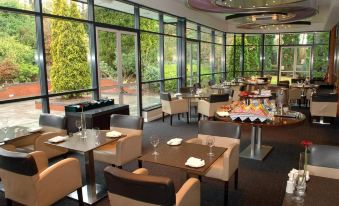 a restaurant with wooden tables and chairs , large windows , and a pool table in the background at Holiday Inn Telford - Ironbridge