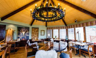 a large dining room with a wooden table and chairs , a chandelier hanging from the ceiling , and windows on the side at The Cock and Bull