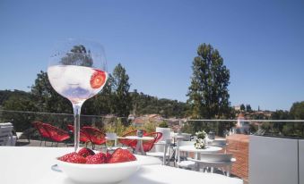 a white table with a large wine glass filled with red wine and strawberries , set in an outdoor patio area at Thomar Boutique Hotel