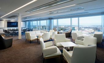 a modern lounge area with white chairs and tables , surrounded by large windows offering views of the city at Gothia Towers & Upper House