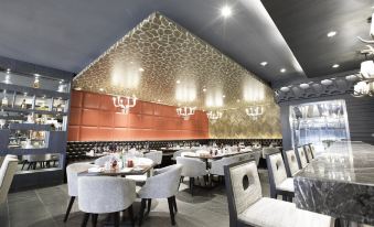 a modern restaurant with white chairs and tables , red ceiling , and a gold patterned wall at bai Hotel Cebu