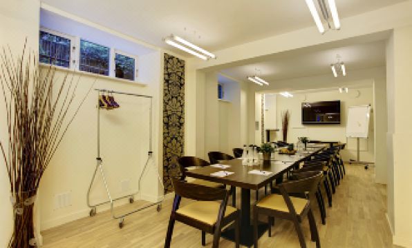 a long dining table surrounded by chairs in a room with hardwood floors and white walls at Hotel Sct. Thomas