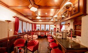 a luxurious restaurant with wooden paneling , red chairs , and a bar area , giving a cozy and elegant atmosphere at Hotel Astoria