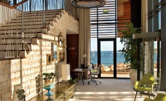 a modern living room with large windows offering an ocean view , and several chairs arranged around the room at Martinhal Sagres Beach Family Resort Hotel