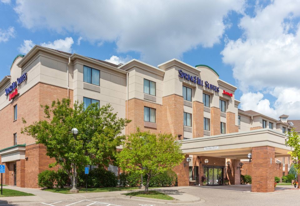 a hampton inn hotel with its name displayed on a building , surrounded by trees and other buildings at SpringHill Suites Minneapolis Eden Prairie