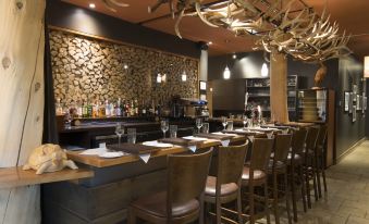 a modern restaurant interior with wooden walls , stone ceiling , and various dining tables and chairs arranged around the bar at Hotel-Musee Premieres Nations