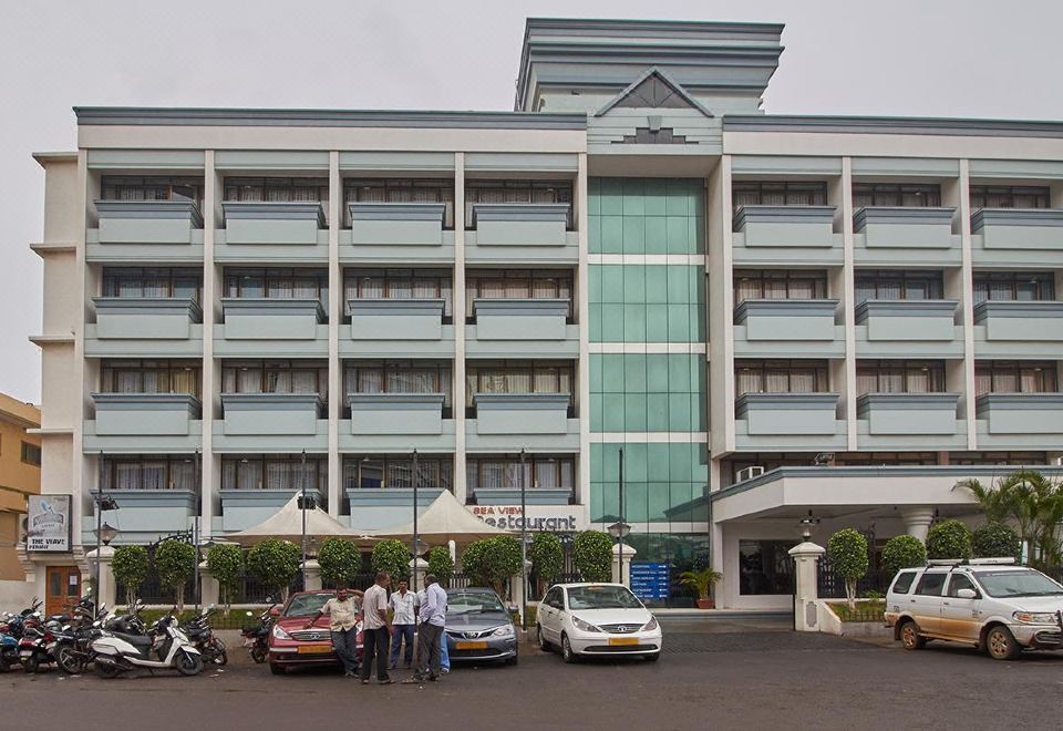 a large , modern hotel building with multiple floors and balconies , surrounded by cars and people on the street at Hotel Sea View