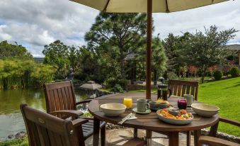 a wooden dining table set up on a patio , with plates of food and utensils placed on the table at Koanze Luxury Hotel & Spa