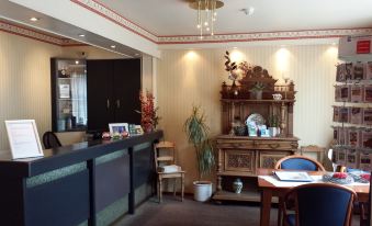 a hotel lobby with a reception desk , chairs , and a dining table , decorated with plants and artwork at Hotel Atlanta