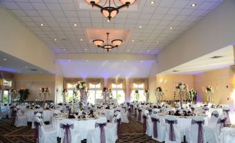 a large banquet hall with multiple dining tables and chairs , all set for a wedding reception at Atkinson Resort & Country Club