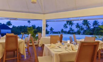 a dining room with tables and chairs set up for a meal , overlooking a body of water at Safari Island