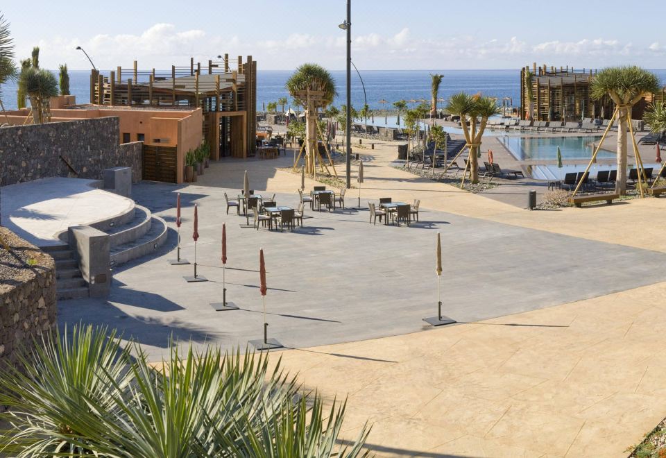 a sandy beach with a group of people sitting on chairs and tables , enjoying the sun and the ocean view at Barceló Tenerife