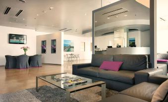 a modern living room with a gray couch , glass coffee table , and an open doorway leading to another area at Garda Hotel