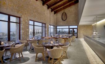 a large dining room with stone walls and wooden beams , featuring multiple tables and chairs arranged for guests to enjoy a meal at The Westin Resort, Costa Navarino