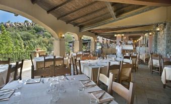 an elegant dining room with tables and chairs arranged for a large group of people to enjoy a meal together at Arbatax Park Resort - Telis