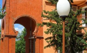 a red brick building with an arched entrance , surrounded by trees and a lamp post at Pomaria