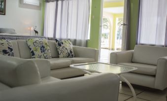 a modern living room with white furniture , including a couch and two armchairs , arranged around a coffee table at Hotel Playa Bonita