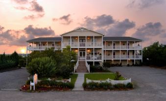 a large white building with multiple balconies , situated in front of a body of water at The Sunset Inn