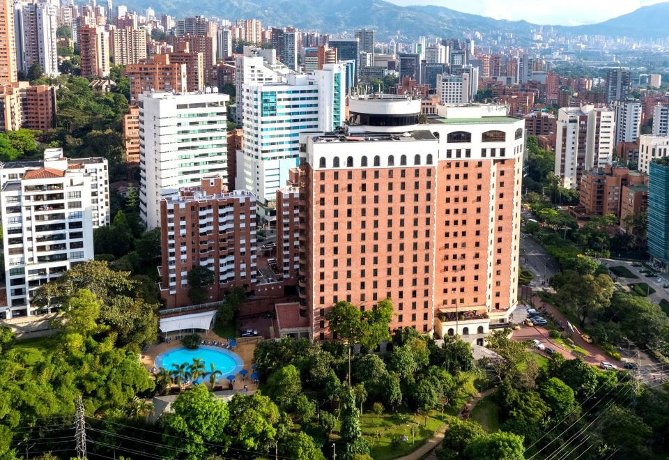 a large hotel surrounded by a cityscape , with a pool visible in the center of the building at Hotel Dann Carlton Medellín