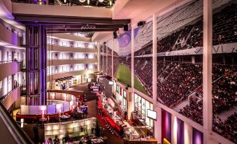 a large indoor event space with a basketball court , multiple sports arenas , and a dining area at Lindner Hotel Leverkusen Bayarena