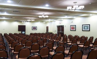 an empty conference room with rows of brown chairs and two paintings on the wall at Holiday Inn Birmingham - Hoover