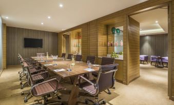 a modern conference room with wooden walls , a long table , and multiple chairs arranged for a meeting at W Goa