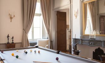 a pool table with a set of cues and balls in front of a window at Château de Fonscolombe