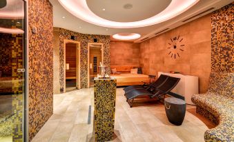 a modern and stylish indoor spa with stone walls , wooden accents , and a large lounge chair at Hotel Helios