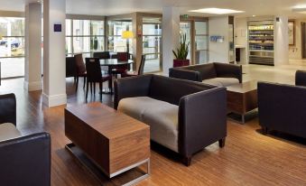 a spacious , well - lit living room with wooden floors and large windows , featuring comfortable seating arrangements and a dining area at Holiday Inn Express Milton Keynes