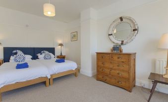 a bedroom with a wooden dresser and a bed , along with some decorative items at The Porthole